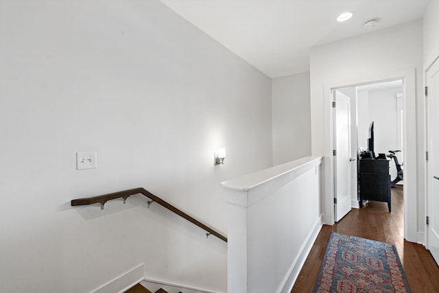 corridor featuring an upstairs landing and dark wood finished floors