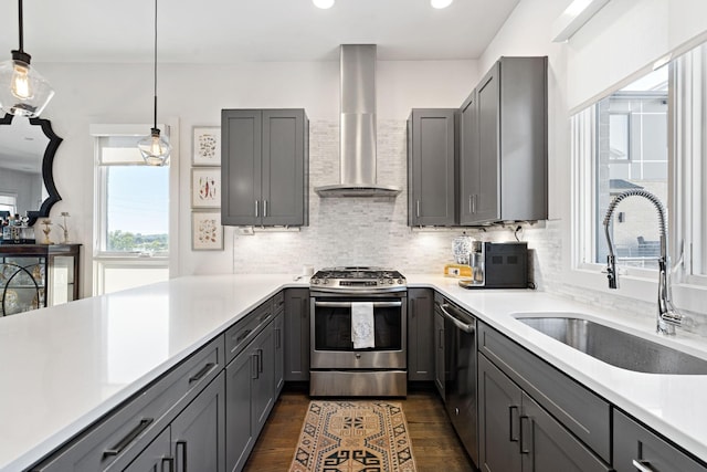kitchen featuring a sink, wall chimney exhaust hood, gray cabinets, and appliances with stainless steel finishes