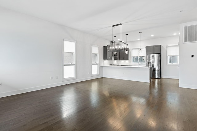 unfurnished living room featuring baseboards, dark wood-style flooring, visible vents, and recessed lighting
