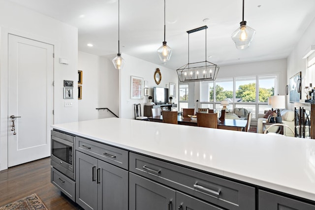 kitchen featuring open floor plan, gray cabinets, light countertops, and stainless steel microwave