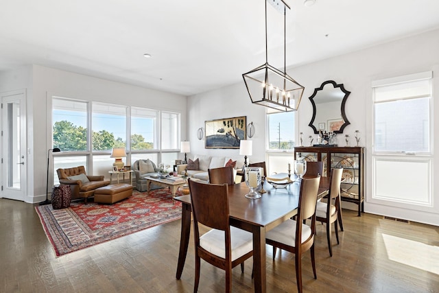dining space featuring dark wood-style floors, a wealth of natural light, visible vents, and a notable chandelier