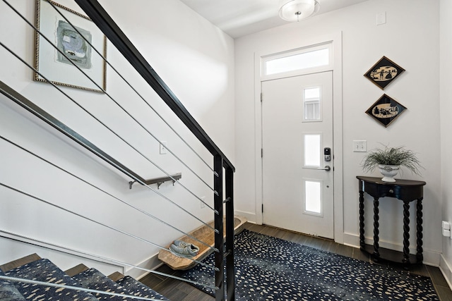foyer entrance featuring a healthy amount of sunlight, stairs, baseboards, and dark wood-style flooring