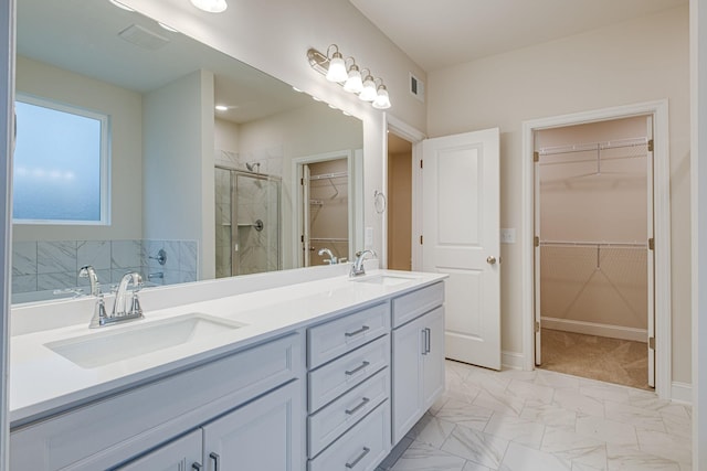 full bath featuring a stall shower, double vanity, marble look tiles, and a spacious closet
