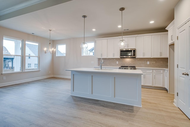 kitchen with stainless steel microwave, a sink, light countertops, backsplash, and light wood-type flooring