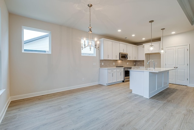 kitchen featuring stainless steel appliances, a sink, a chandelier, light countertops, and baseboards