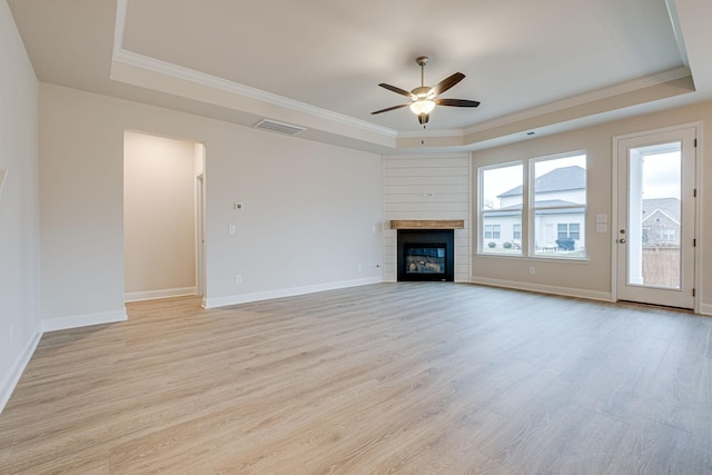 unfurnished living room with a raised ceiling, ceiling fan, ornamental molding, light wood-style flooring, and baseboards