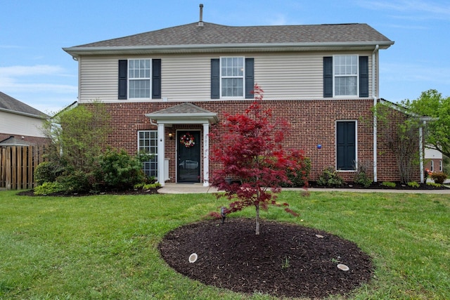 view of front of home with brick siding, fence, and a front yard