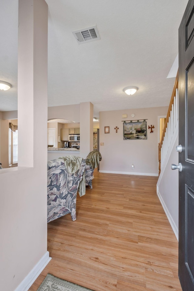 interior space featuring baseboards, arched walkways, wood finished floors, and visible vents