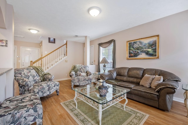 living room featuring light wood-type flooring, stairs, and baseboards