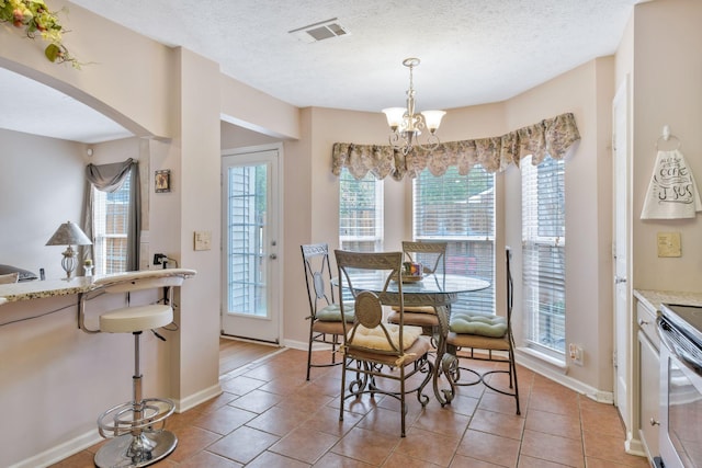 dining space with a notable chandelier, arched walkways, a textured ceiling, baseboards, and visible vents