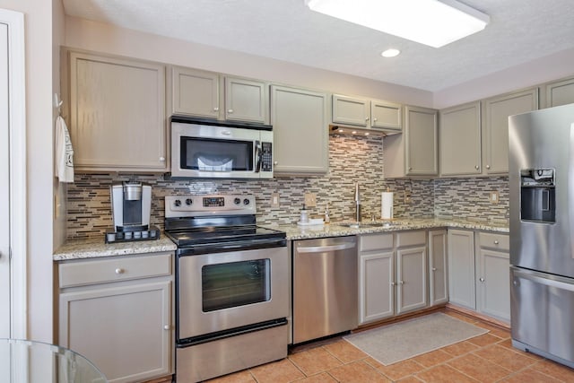 kitchen with a sink, appliances with stainless steel finishes, gray cabinets, and backsplash