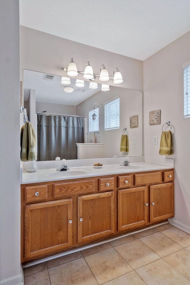 bathroom with a sink, tile patterned flooring, double vanity, a shower with shower curtain, and visible vents