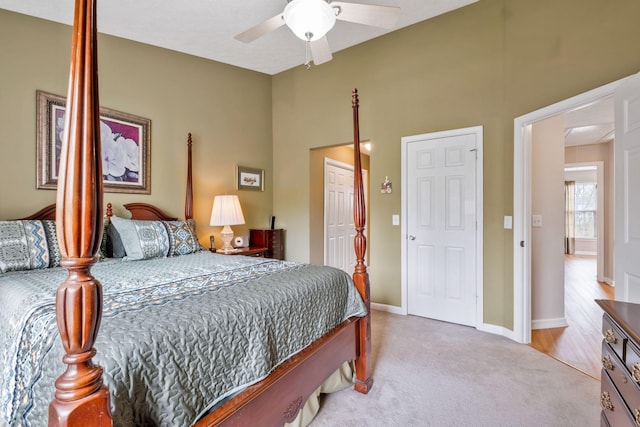 bedroom with ceiling fan, light colored carpet, baseboards, and a closet