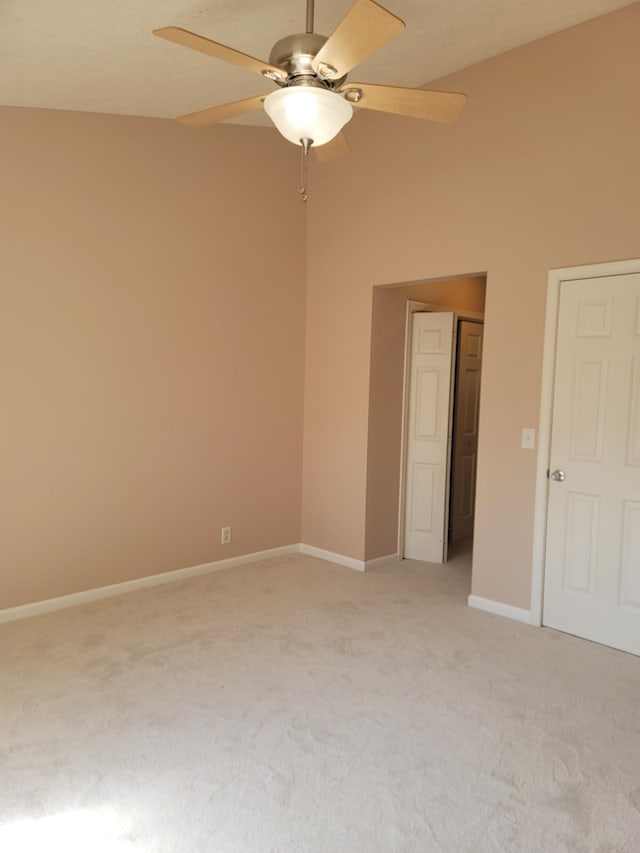 spare room featuring ceiling fan, light carpet, and baseboards