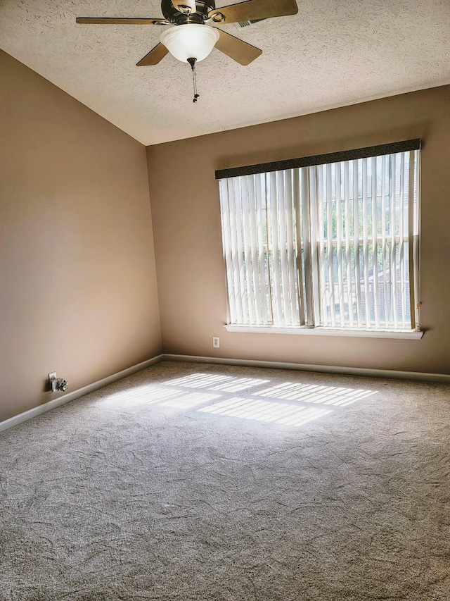 carpeted empty room with baseboards, a ceiling fan, and a textured ceiling
