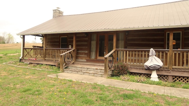 exterior space with a yard, a chimney, metal roof, and a deck