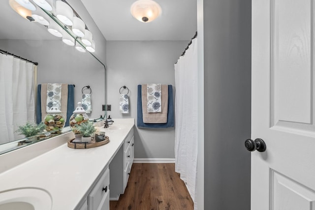full bathroom with a sink, wood finished floors, baseboards, and double vanity