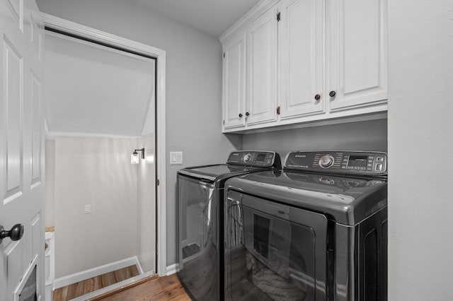 washroom with washer and clothes dryer, wood finished floors, cabinet space, and baseboards