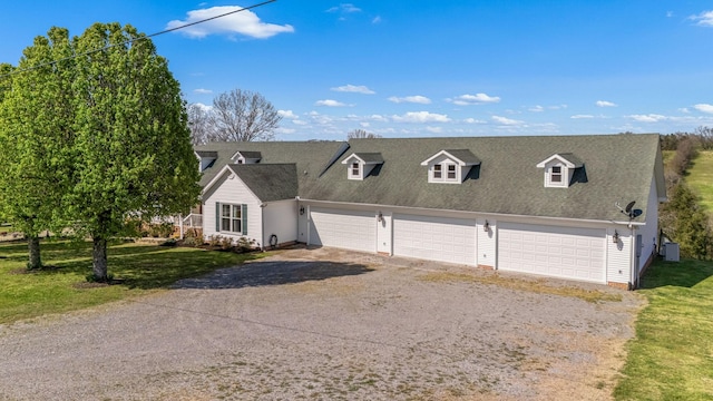 view of front facade with a front lawn, driveway, a detached garage, and roof with shingles