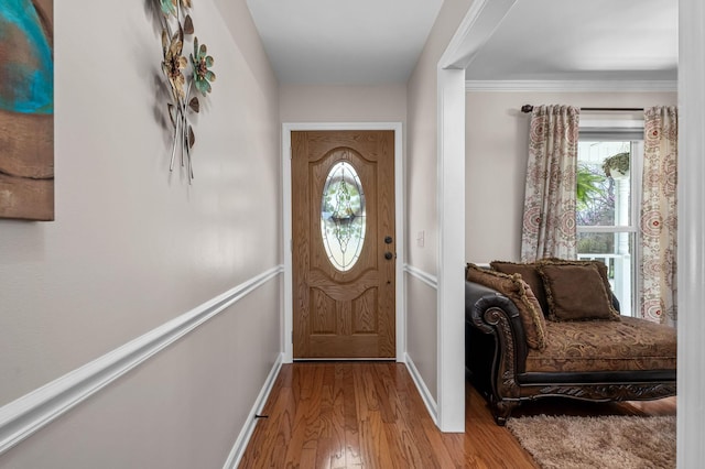 entryway with baseboards, crown molding, and wood finished floors