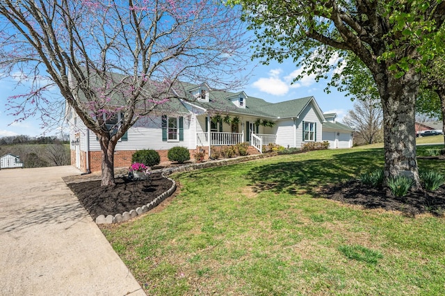 new england style home featuring a front lawn, driveway, an attached garage, and a porch