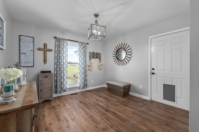 interior space with baseboards, visible vents, wood finished floors, and an inviting chandelier