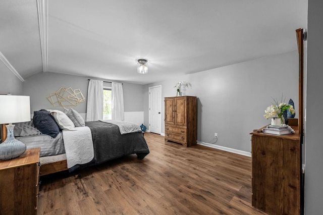 bedroom with baseboards, wood finished floors, and vaulted ceiling