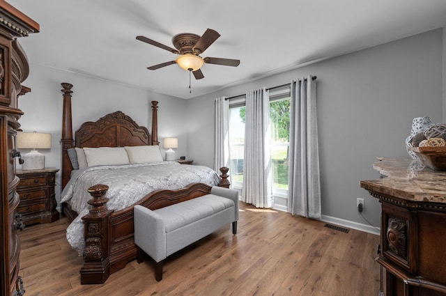 bedroom featuring baseboards, visible vents, a ceiling fan, and wood finished floors