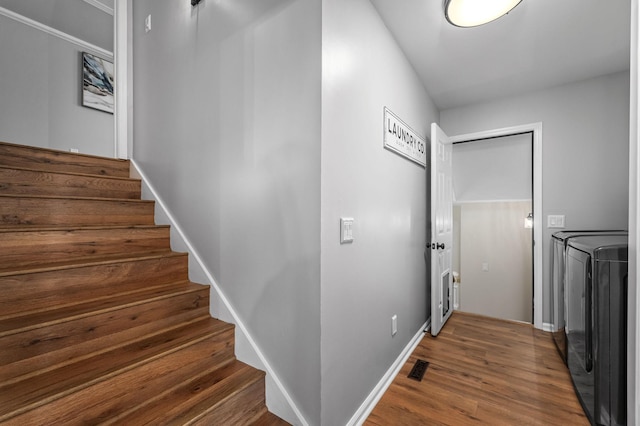 staircase with washing machine and clothes dryer, visible vents, baseboards, and wood finished floors