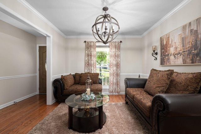 living area featuring baseboards, ornamental molding, wood finished floors, and a notable chandelier