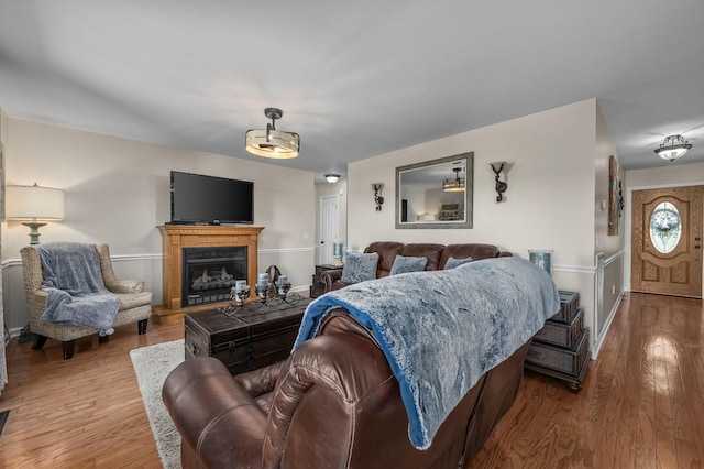 living room featuring baseboards, wood finished floors, and a fireplace with raised hearth