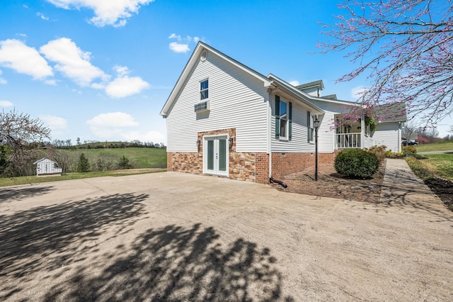 view of home's exterior with a patio area, driveway, stone siding, and french doors