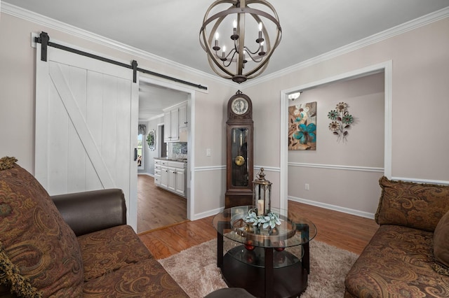 living area with a notable chandelier, crown molding, a barn door, wood finished floors, and baseboards