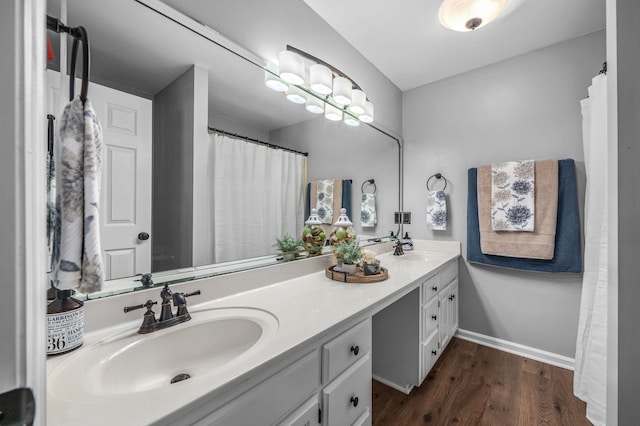 bathroom featuring double vanity, a sink, baseboards, and wood finished floors