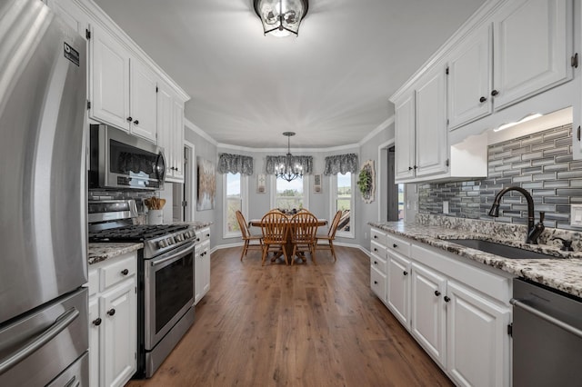 kitchen featuring white cabinetry, a sink, a notable chandelier, and appliances with stainless steel finishes