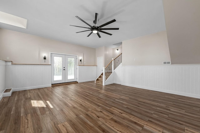 unfurnished living room featuring stairs, french doors, a ceiling fan, wood finished floors, and visible vents