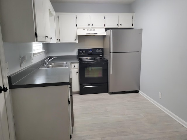 kitchen featuring under cabinet range hood, a sink, dark countertops, black range with electric cooktop, and freestanding refrigerator