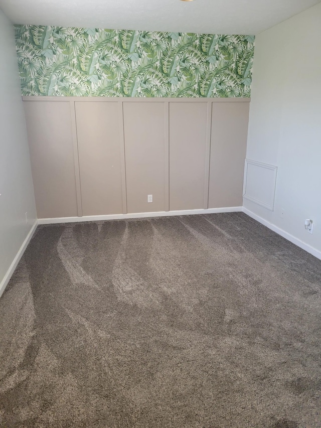carpeted empty room with wainscoting, a decorative wall, and wallpapered walls