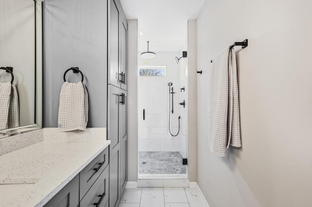full bath featuring marble finish floor, vanity, a stall shower, and baseboards