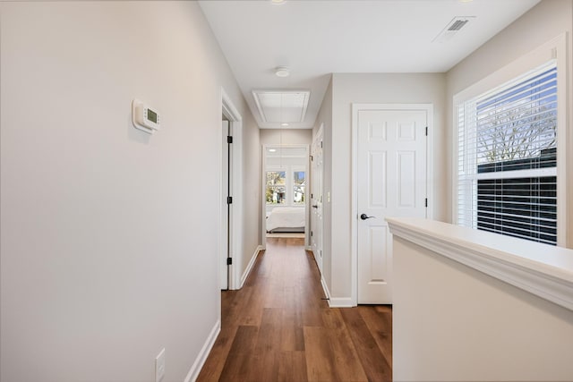 hallway with attic access, baseboards, dark wood-style flooring, and a healthy amount of sunlight