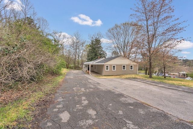 view of side of home featuring aphalt driveway and a chimney