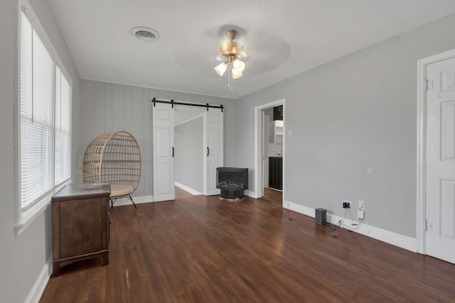 interior space with baseboards, a barn door, visible vents, and wood finished floors
