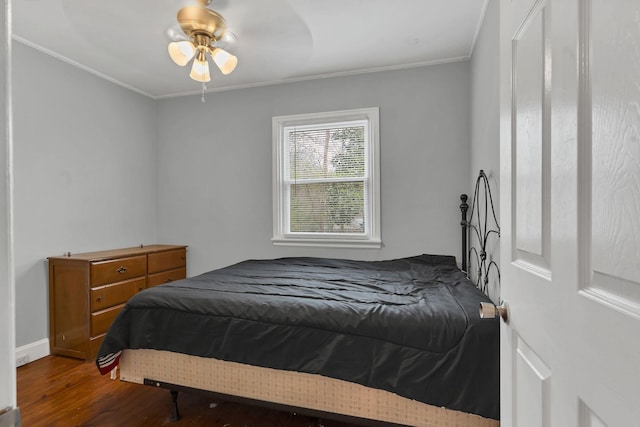 bedroom with a ceiling fan, crown molding, baseboards, and wood finished floors