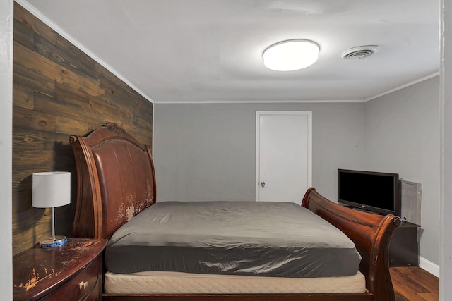 bedroom featuring visible vents, crown molding, wood finished floors, and wooden walls