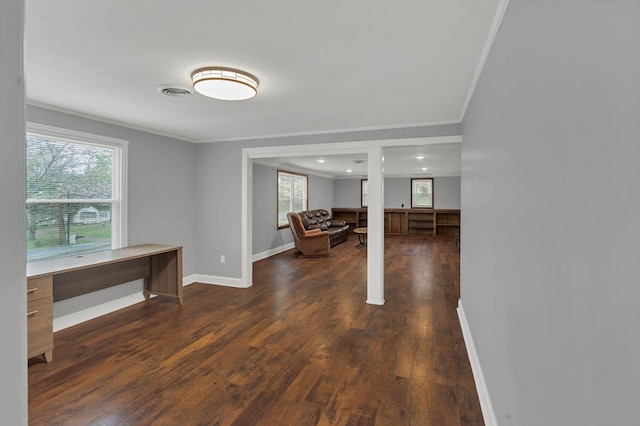 interior space with dark wood-type flooring, baseboards, visible vents, and crown molding