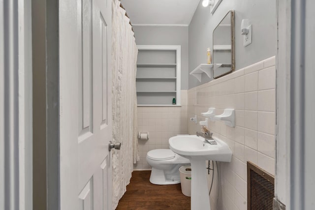 bathroom featuring tile walls, toilet, wainscoting, and wood finished floors