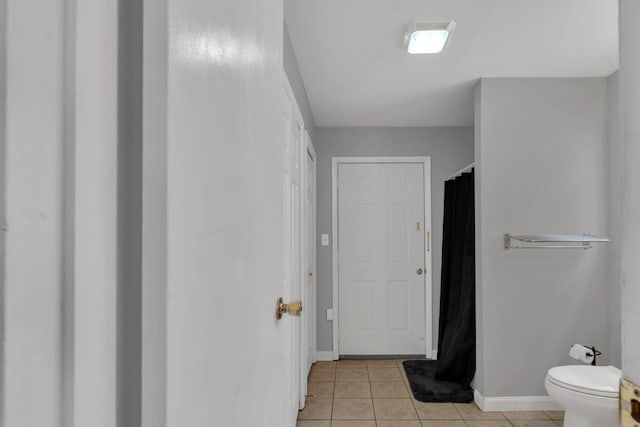 bathroom with baseboards, a shower with shower curtain, toilet, and tile patterned flooring