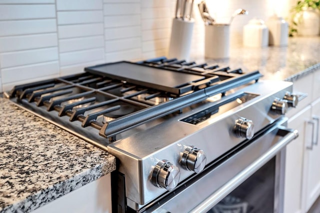 details featuring stainless steel range with gas stovetop, white cabinetry, and light stone counters