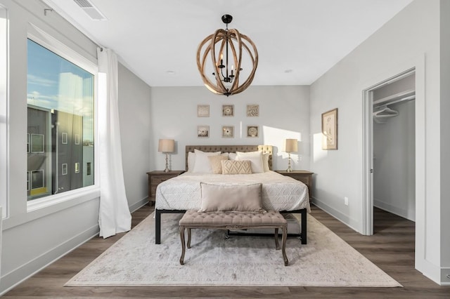 bedroom with a walk in closet, baseboards, visible vents, dark wood-type flooring, and an inviting chandelier
