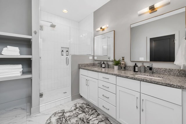 full bath with marble finish floor, a sink, a stall shower, and double vanity